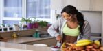 Fit dark skinned woman cutting healthy vegetables and fruits.