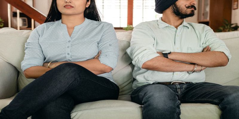 Image of a man and a woman displaying defensive posture by crossing their arms and looking away from each other.